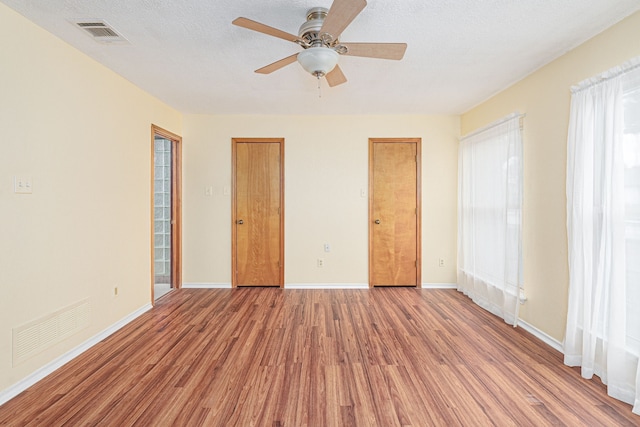 unfurnished bedroom with a textured ceiling, light wood-type flooring, and ceiling fan