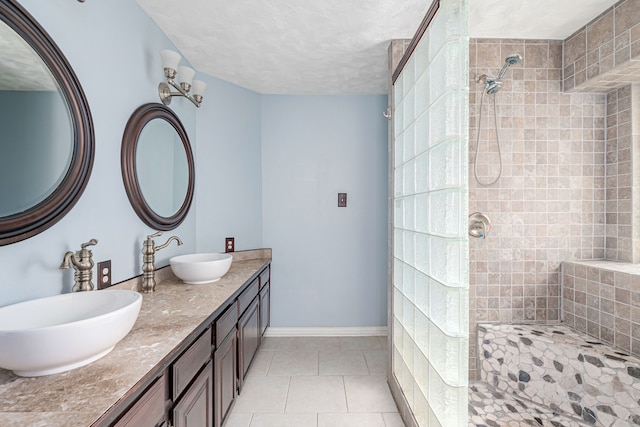 bathroom featuring a tile shower, tile patterned flooring, and vanity