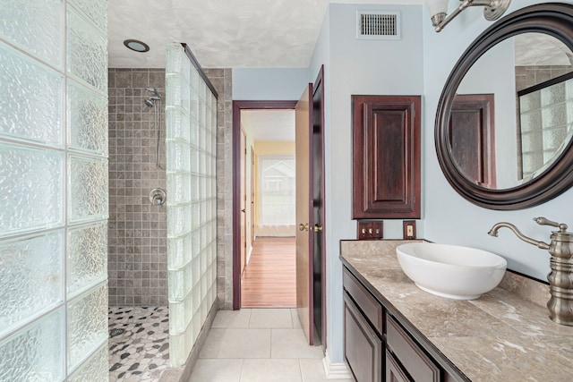 bathroom with vanity, a tile shower, and tile patterned floors