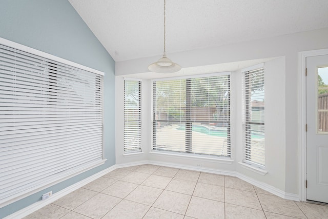 interior space featuring light tile patterned floors, a textured ceiling, and lofted ceiling