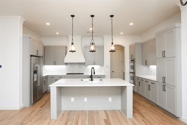 kitchen featuring stainless steel appliances, sink, a center island with sink, and gray cabinetry