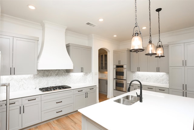 kitchen with sink, hanging light fixtures, gas cooktop, custom range hood, and stainless steel double oven