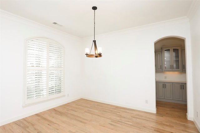 unfurnished dining area featuring a chandelier, light hardwood / wood-style floors, and crown molding