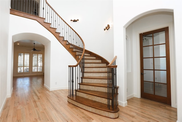 staircase with ceiling fan and hardwood / wood-style floors