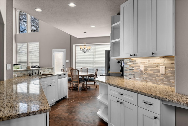 kitchen with dishwasher, hanging light fixtures, light stone countertops, white cabinets, and sink