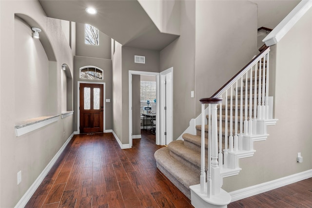 entryway featuring dark hardwood / wood-style floors, a towering ceiling, and a healthy amount of sunlight