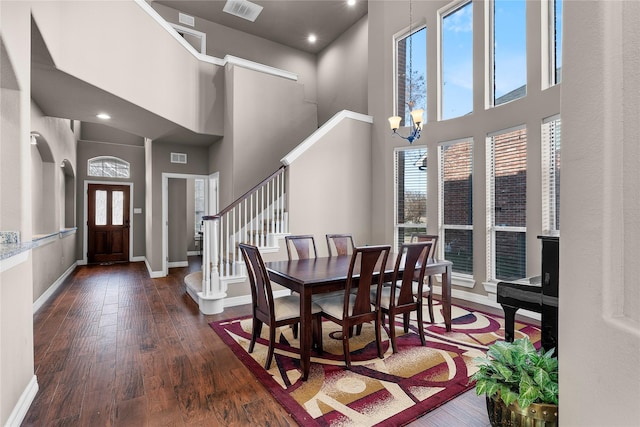 dining area featuring a towering ceiling, a chandelier, and dark hardwood / wood-style floors