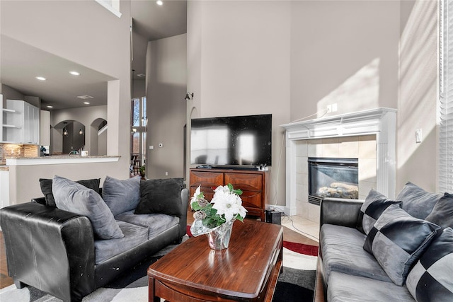 living room with a high ceiling and a tiled fireplace