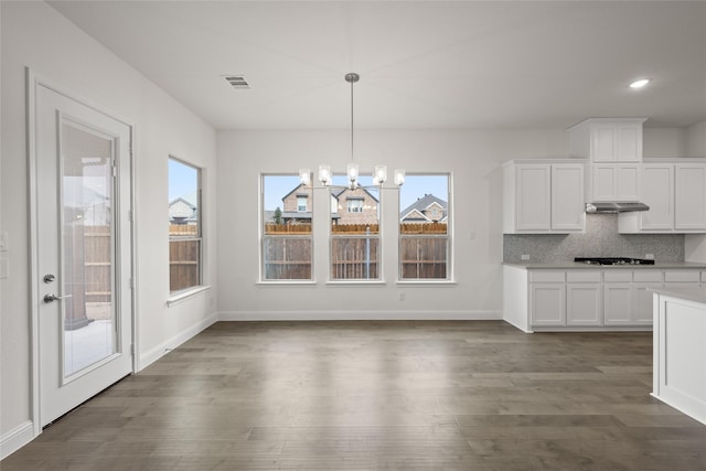 unfurnished dining area featuring visible vents, a healthy amount of sunlight, and dark wood-style flooring