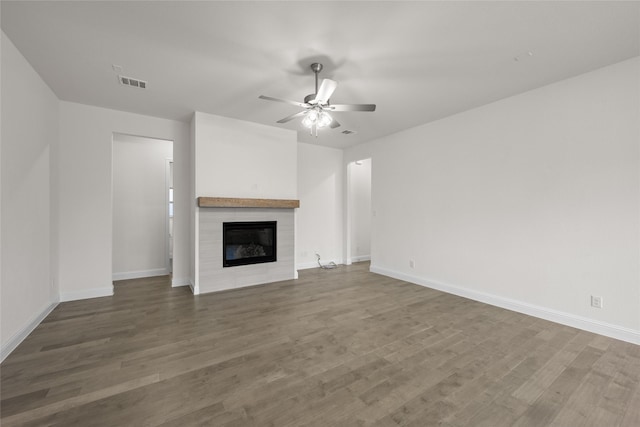 unfurnished living room featuring wood finished floors, baseboards, visible vents, a fireplace, and ceiling fan