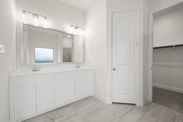 full bathroom with double vanity, marble finish floor, baseboards, and a sink