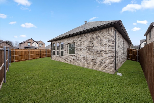 rear view of property featuring brick siding, roof with shingles, a fenced backyard, and a lawn