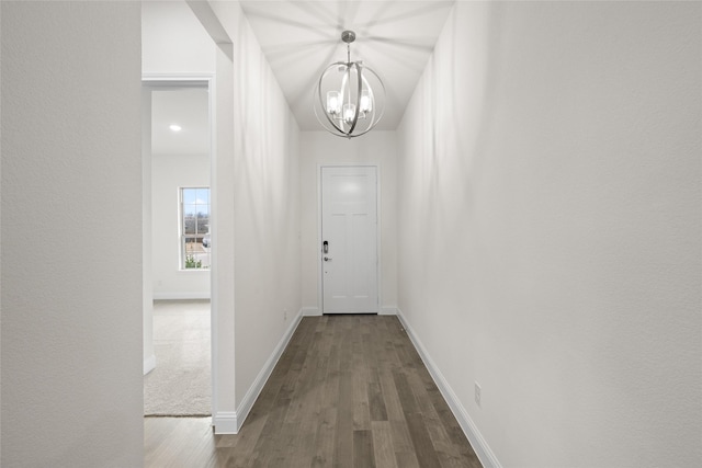 doorway with dark wood finished floors, a chandelier, and baseboards