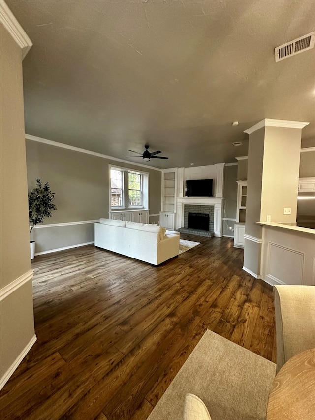 unfurnished living room featuring dark wood-type flooring, ceiling fan, crown molding, and built in shelves