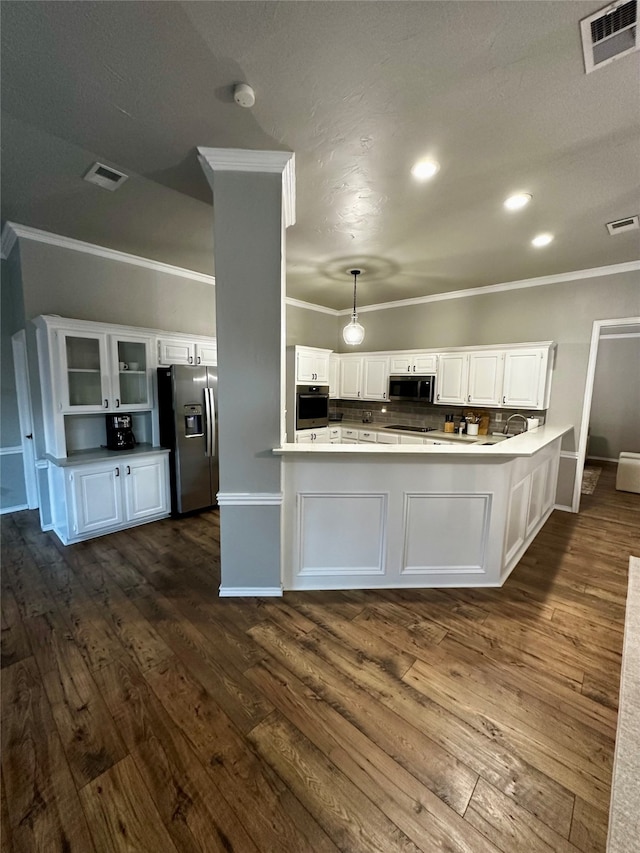 kitchen featuring dark hardwood / wood-style flooring, kitchen peninsula, stainless steel appliances, pendant lighting, and white cabinets