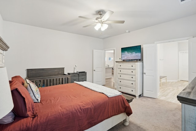 bedroom featuring ceiling fan, light colored carpet, and ensuite bathroom