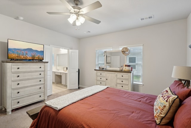 bedroom with ceiling fan, light carpet, connected bathroom, and multiple windows