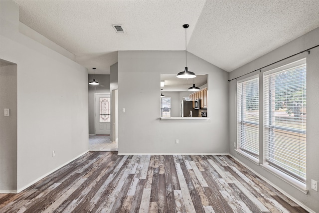 unfurnished living room featuring hardwood / wood-style floors, a textured ceiling, and vaulted ceiling