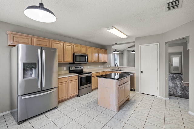 kitchen featuring a textured ceiling, appliances with stainless steel finishes, sink, and decorative light fixtures