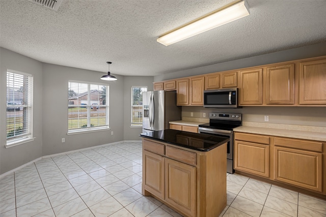 kitchen with appliances with stainless steel finishes, a textured ceiling, light tile patterned floors, hanging light fixtures, and a center island