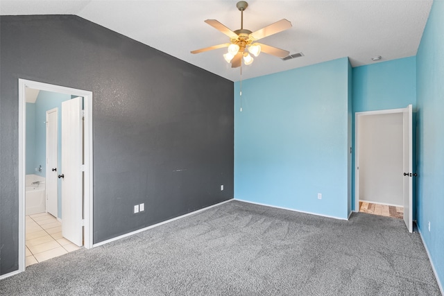 carpeted spare room featuring ceiling fan and vaulted ceiling