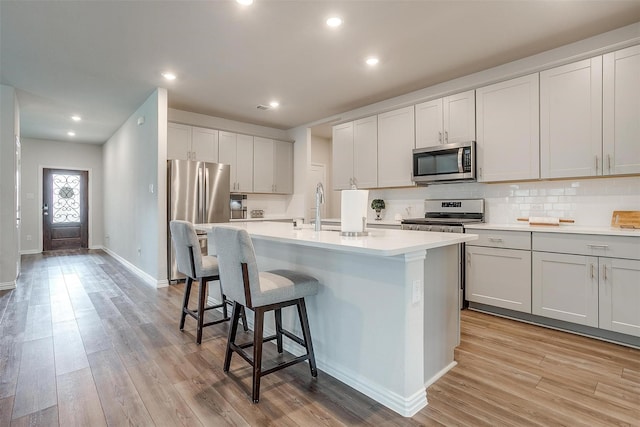 kitchen featuring sink, appliances with stainless steel finishes, light hardwood / wood-style flooring, and a kitchen island with sink