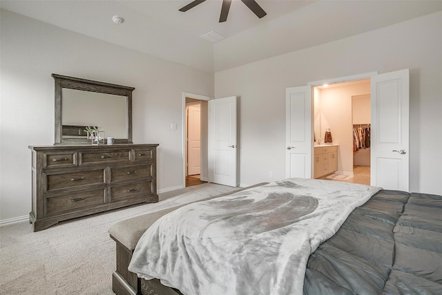 bedroom with ensuite bathroom, light colored carpet, and ceiling fan