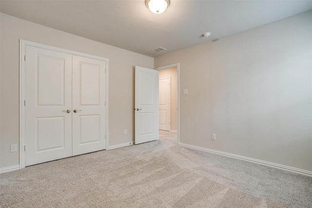 unfurnished bedroom with a closet and light colored carpet