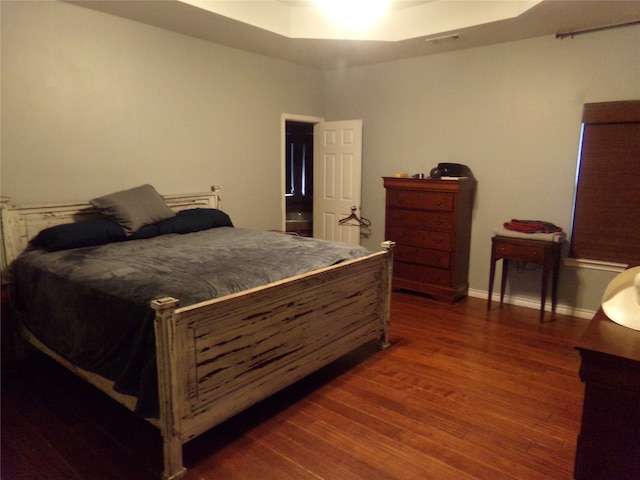 bedroom featuring dark hardwood / wood-style floors and a raised ceiling