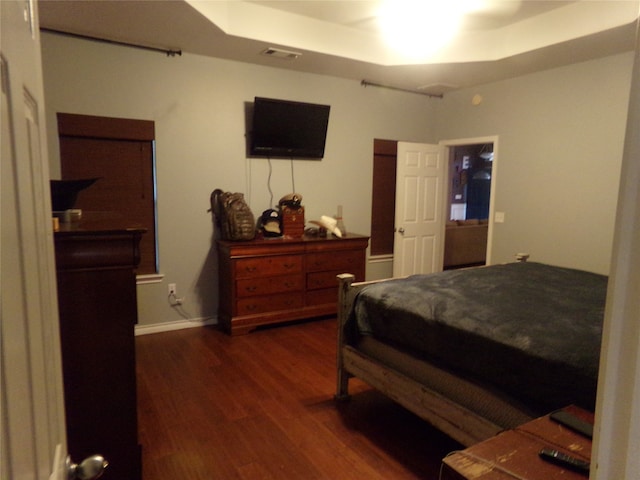 bedroom featuring dark hardwood / wood-style flooring and a tray ceiling