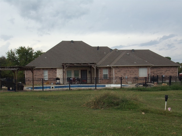 rear view of house with a lawn and a fenced in pool