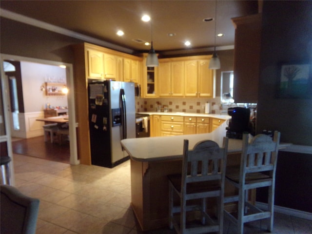 kitchen featuring light brown cabinetry, pendant lighting, kitchen peninsula, and stainless steel fridge