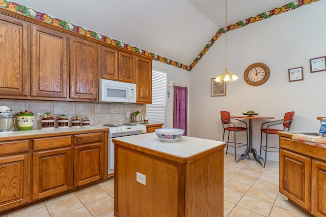 kitchen with lofted ceiling, decorative light fixtures, a kitchen island, white appliances, and backsplash