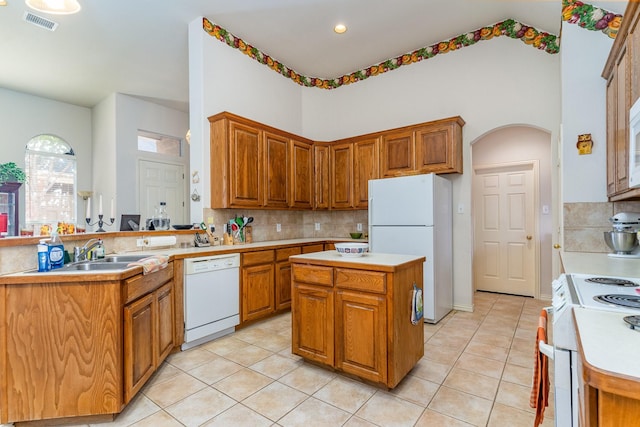 kitchen featuring tasteful backsplash, white appliances, a center island, and sink