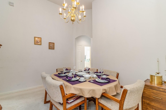 dining space with a towering ceiling, light colored carpet, and a chandelier