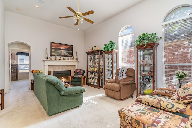 carpeted living room featuring a tile fireplace, lofted ceiling, and ceiling fan