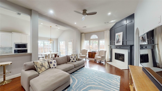 living room featuring ceiling fan, plenty of natural light, dark wood-type flooring, and vaulted ceiling