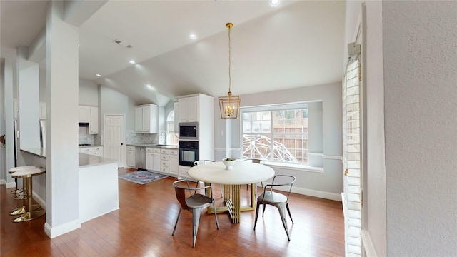 dining space featuring hardwood / wood-style floors, high vaulted ceiling, a chandelier, and sink