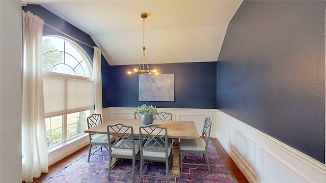 dining space with dark wood-type flooring, vaulted ceiling, a healthy amount of sunlight, and a notable chandelier