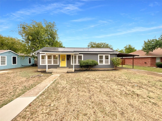 single story home with a porch, solar panels, and a carport