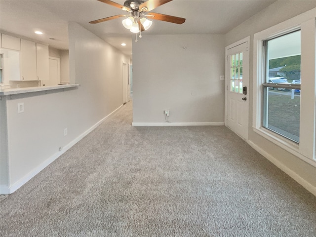 unfurnished living room with a wealth of natural light, ceiling fan, and light colored carpet