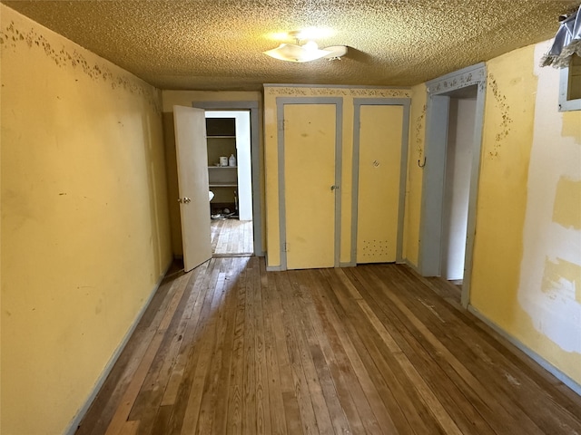 corridor featuring a textured ceiling and hardwood / wood-style floors