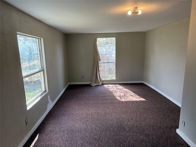 spare room with dark colored carpet