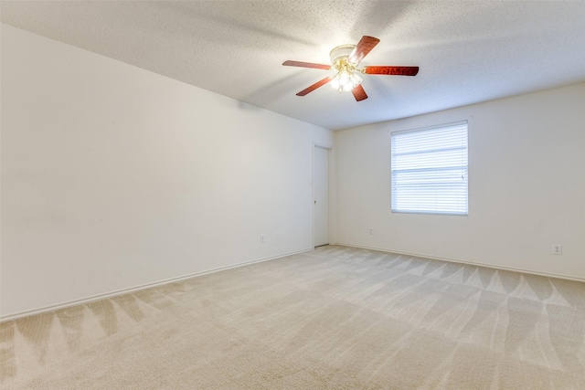 spare room featuring ceiling fan, light carpet, and a textured ceiling