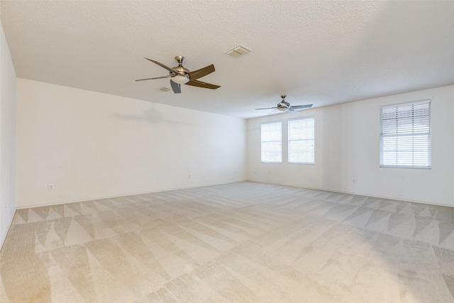 unfurnished room with ceiling fan, light colored carpet, and a textured ceiling