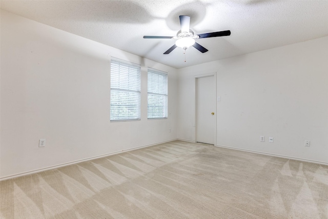 spare room featuring ceiling fan, light colored carpet, and a textured ceiling