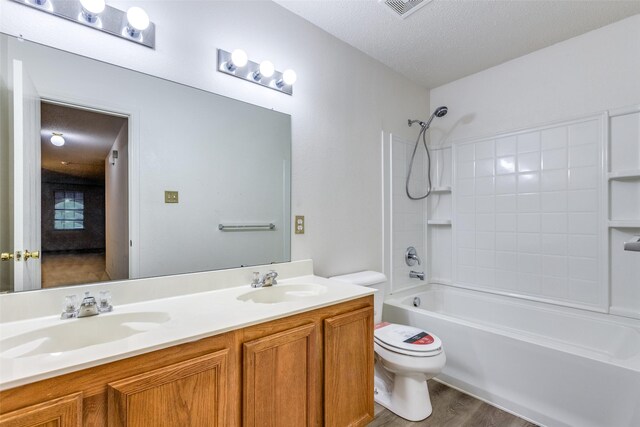 full bathroom with vanity, wood-type flooring, a textured ceiling, shower / bathtub combination, and toilet