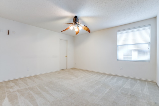 unfurnished room with ceiling fan, a textured ceiling, and light colored carpet