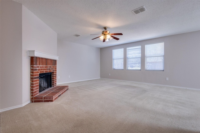 unfurnished living room featuring ceiling fan, light colored carpet, a fireplace, and a textured ceiling