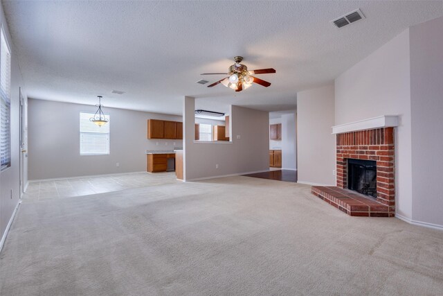 unfurnished living room featuring a textured ceiling, hardwood / wood-style flooring, ceiling fan, and a brick fireplace